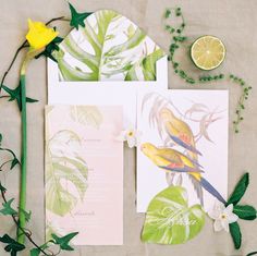 two cards with flowers, lemons and greenery are on the table next to each other