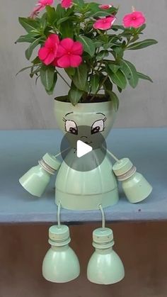 a green robot planter with pink flowers in it