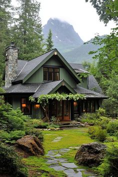 a house in the woods with green grass and rocks on the path leading to it