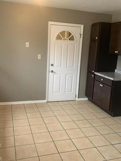 an empty kitchen with tile flooring and dark wood cabinetry in the backround