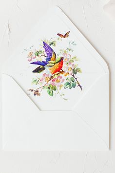 a white envelope with a bird and flowers on it, next to a small butterfly