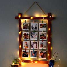 a wooden frame with pictures hanging on it and lights strung from the wall behind it