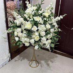 a vase filled with white flowers sitting on top of a floor next to a mirror