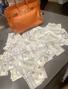 a pile of money sitting on top of a table next to a handbag and purse