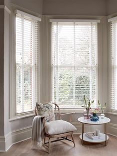 a living room filled with furniture and two large windows covered in white shuttered blinds