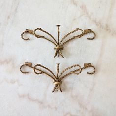 three decorative brass hooks on a marble surface