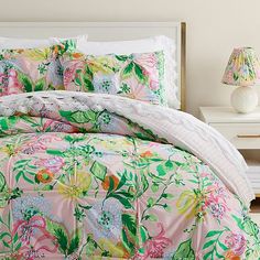 a bed covered in pink and green floral comforter sets with matching pillow shampoos