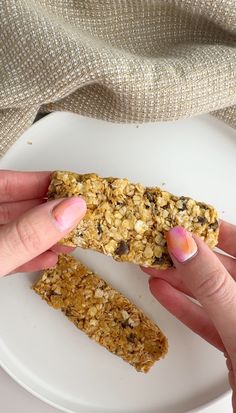 two hands holding an oatmeal bar on a plate