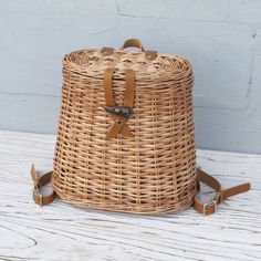 a brown wicker backpack sitting on top of a white wooden table next to a wall