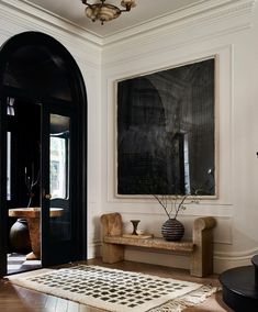 a black and white area rug in front of a doorway with a painting on the wall