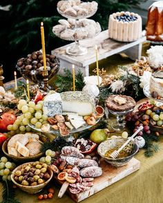 a table topped with lots of different types of food next to candles and desserts