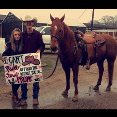 two people standing next to a horse holding a sign