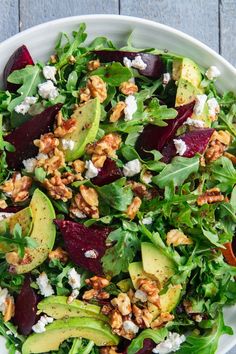 a salad with beets, avocado and feta cheese in a white bowl