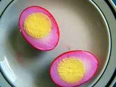 two halves of an egg with yellow and pink inside on a white plate next to a blue table cloth