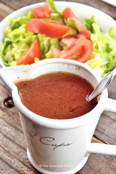 there is a bowl of salad and a cup of soup on the table