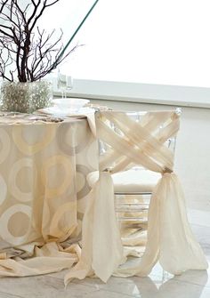 the table is covered with sheer curtains and has a vase on it next to it