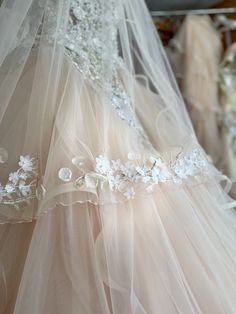 a wedding dress hanging on a rack in a room with other dresses and veils