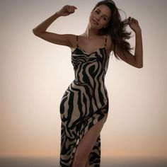 a woman in a zebra print dress posing for the camera with her arms behind her head