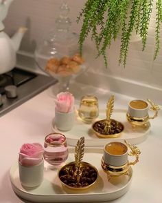 there is a tray with cups and saucers on it, next to a potted plant