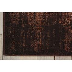 a brown area rug on top of a wooden floor next to a white tile wall