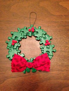 a christmas wreath shaped ornament hanging on a wooden table with a red bow