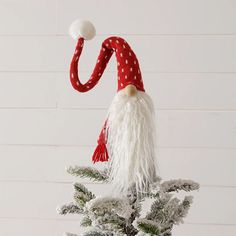 a gnome ornament hanging from a christmas tree with white and red decorations on it