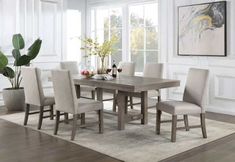 a dining room table with chairs and a potted plant