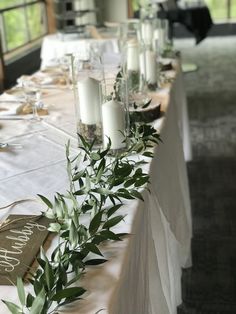 a long table with candles and greenery on it