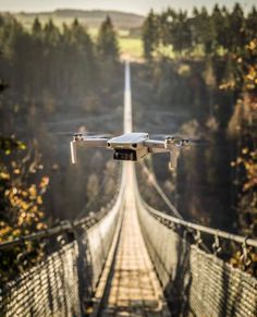 a white unmanned flying over a suspension bridge