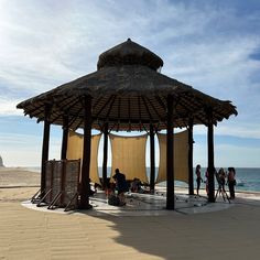 people are standing under a gazebo on the beach