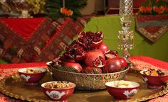 a table topped with bowls filled with pomegranates and other food items