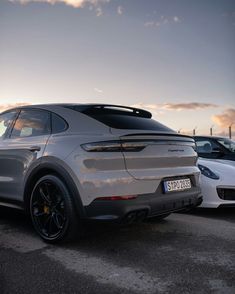 two porsche cayens parked next to each other in a parking lot at sunset