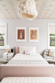 a white bed sitting in a bedroom next to two pictures on the wall above it