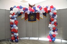 an arch made out of balloons in the middle of a room with a flag on it