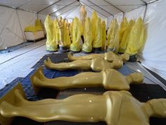 several yellow mannequins are lined up in a tent