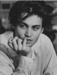 a black and white photo of a young man with his hand on his chin looking at the camera