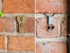 a brick wall with two pieces of metal attached to it and a plant growing out of the middle