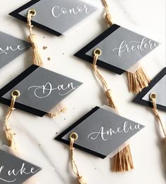 graduation caps with tassels and name tags are arranged on a white table top