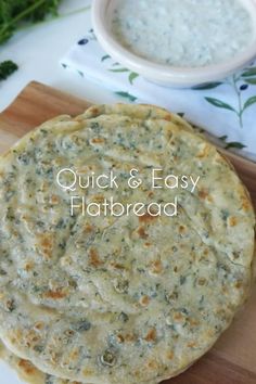 two flatbreads sitting on top of a cutting board next to a bowl of dip