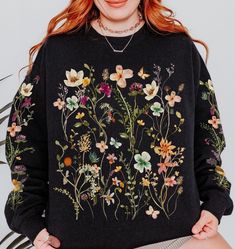 ❤️ Vintage pressed wildflower design exclusively from TheCocoBear ❤️ Be transported to a blooming meadow with our unique crewneck that features delicate watercolor pressed wildflowers on the front and down both sleeves. Each petal and leaf is meticulously rendered to create a whimsical, nature-inspired masterpiece. Whether you're strolling through sunlit fields, sipping tea by the fire, or simply yearning for a touch of cottagecore flair, this sweatshirt is sure to make the perfect gift for yourself or anyone who wants to carry spring with them all year. ❤️ Super-soft & cozy sweatshirt with a vintage look and feel. ❤️To ensure sizing, refer to size chart in photos and compare measurements to those of a sweatshirt you already own that fits well. ❤️ Cotton/poly blend. ❤️ Non-toxic, eco-frien Oversized Floral Print Sweatshirt For Spring, Black Floral Print Sweatshirt For Spring, Spring Long Sleeve Botanical Sweatshirt, Cottagecore Floral Embroidery Fall Top, Cottagecore Floral Embroidered Fall Top, Cottagecore Floral Embroidery Top For Fall, Cottagecore Floral Embroidered Top For Fall, Fall Cottagecore Floral Embroidery Top, Oversized Floral Print Sweatshirt For Fall