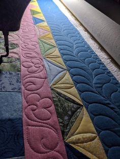 a close up of a quilted table runner on the floor next to a chair