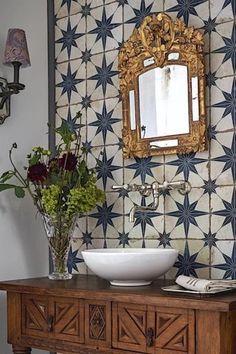 a bathroom with a sink, mirror and flowers on the counter top in front of it