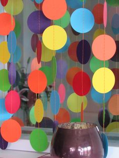 a vase sitting on top of a table next to a window covered in paper circles