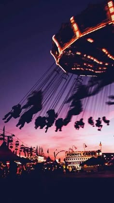 an amusement park at night with people riding on swings and carousels in the background