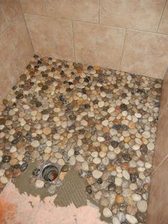 a bathroom with rocks on the floor and a drain in the shower stall that is filled with water