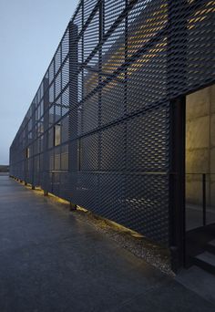 an empty parking lot next to a building with a large metal fence on it's side