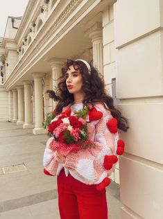 a woman in red pants is holding flowers