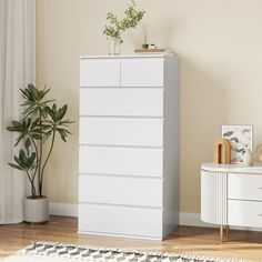 a white dresser sitting next to a plant in a living room