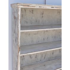 an old white bookcase with three shelves on the front and one shelf in the back