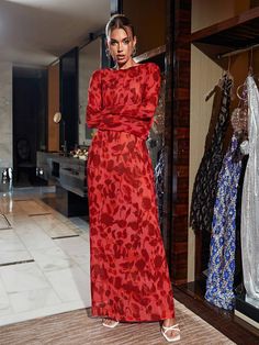 a woman in a red dress standing next to a rack with dresses on hangers